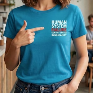 May include: A teal t-shirt with the text "HUMAN SYSTEM FAILURE CONTACT COFFEE IMMEDIATELY" in white and red. The shirt is being pointed at.