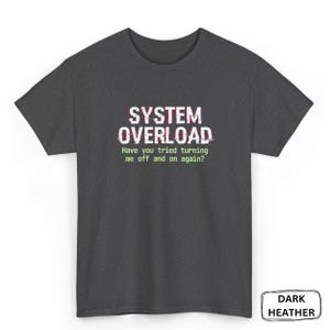 May include: Dark heather gray t-shirt with the text "SYSTEM OVERLOAD" in white with red and green glitch effects. The shirt also has the text "Have you tried turning me off and on again?"