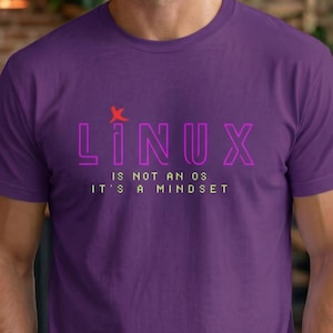 May include: Purple t-shirt with the word "LINUX" in a neon-style font, with a small red graphic above the "I". Below the word "LINUX" is the text "IS NOT AN OS IT'S A MINDSET" in a smaller font.