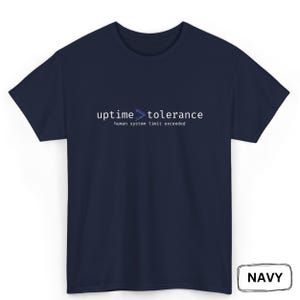 Puede incluir: Camiseta azul marino con el texto "uptime > tolerance" y "human system limit exceeded" en blanco. El texto "uptime > tolerance" tiene un símbolo de mayor que morado y azul. Cuello redondo.
