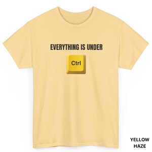 Peut inclure: Un t-shirt à manches courtes jaune clair avec le texte noir "EVERYTHING IS UNDER" placé au-dessus d'un graphique représentant une touche de clavier d'ordinateur jaune marquée "Ctrl". Le t-shirt a un col rond et une coupe standard.