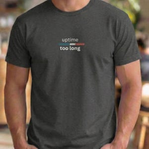May include: Dark gray t-shirt with the words "uptime too long" in white font. Above the text is a horizontal bar with blue, teal, and red segments. The shirt is short-sleeved and made of a soft material.