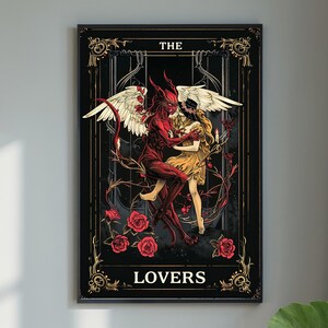 Puede incluir: Una impresión artística enmarcada con una ilustración gótica oscura de dos figuras abrazándose. Una es roja con cuernos y alas, la otra con un vestido amarillo y alas blancas. Las palabras "THE LOVERS" están en la parte inferior.