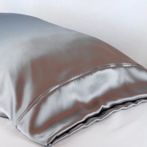 May include: A silver satin pillowcase with a smooth, silky texture.
