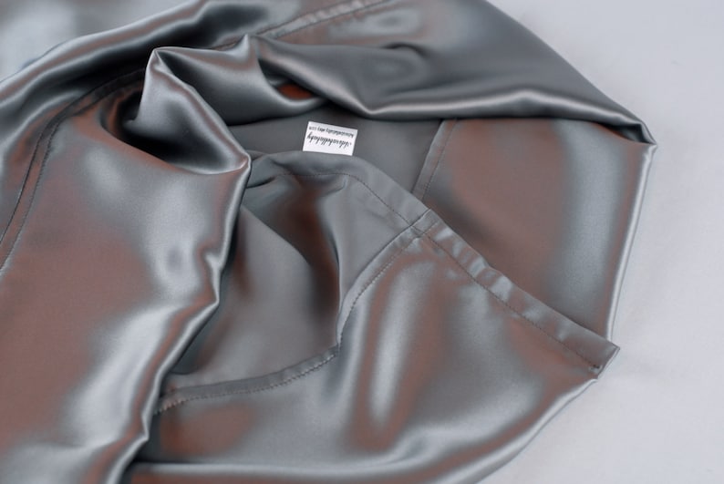 May include: A silver satin pillowcase with a white label that says "remarkable".