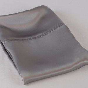 May include: A folded gray satin pillowcase. The pillowcase is smooth and silky.