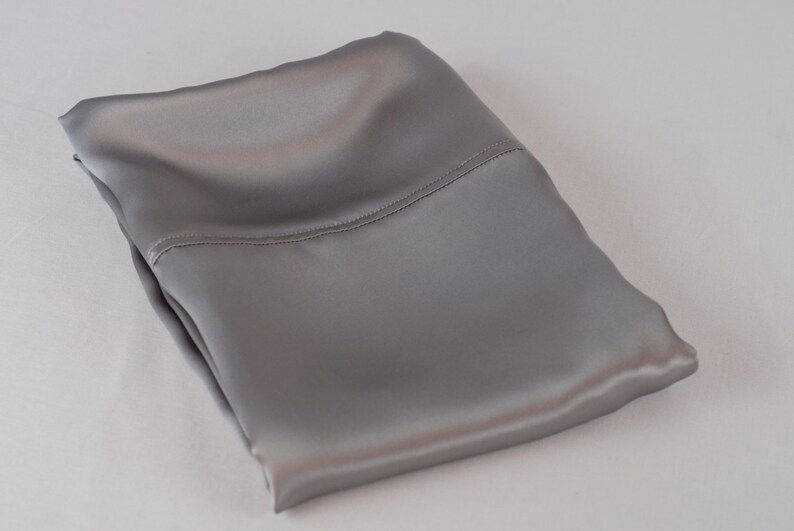 May include: A folded gray satin pillowcase. The pillowcase is smooth and silky.
