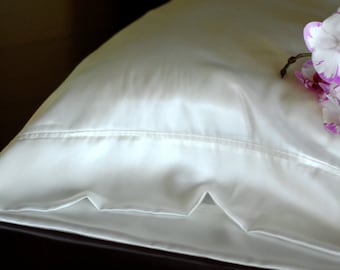 May include: A white satin pillowcase with a decorative edge and a pink orchid flower on top.