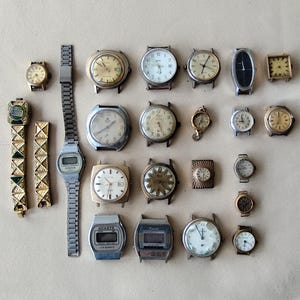 Può includere: Una collezione di orologi da polso vintage in vari stili e dimensioni. Gli orologi presentano quadranti rotondi, quadrati e rettangolari con cinturini in metallo e pelle. Alcuni orologi hanno casse dorate, altri display digitali.