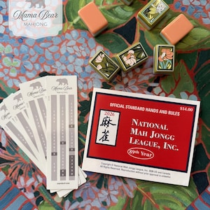 May include: A set of Mahjong tiles with floral and dragon designs, several white score cards labeled Mama Bear Mahjong, and a red National Mah Jongg League 2026 official standard hands and rules card featuring the text 89th Year and 2026.