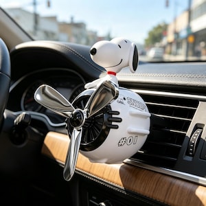 May include: A white car air freshener shaped like an aeroplane engine with a Snoopy figure on top. The device features a metallic silver propeller, black interior vents, and the text SNOOPY and #01 printed in black on the side of the white casing.