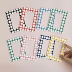 May include: A collection of rectangular photo frames in various colors, including black, red, blue, green, pink, navy, and yellow. Each frame features a classic gingham pattern, offering a charming and decorative touch for displaying photos.