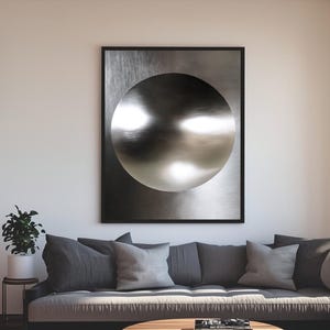 May include: A contemporary living room featuring a grey sofa, a circular wooden coffee table, and two dark grey ottomans. An abstract artwork hangs above the sofa. The room has wooden flooring and a large window.