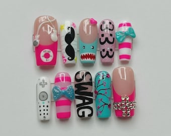 May include: A set of ten artificial nails with various designs. The designs include a pink and white striped nail with a bow, a remote control, a mustache, a shark, the word "SWAG", and a nail with a pink and white design with a bow.