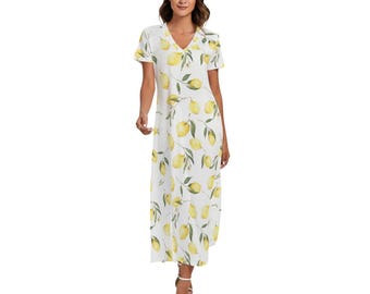 May include: A white, ankle-length dress with a V-neck and short sleeves. The dress is adorned with a pattern of yellow lemons and green leaves. The model is wearing white sandals.