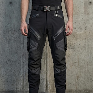 May include: Black tactical cargo pants featuring multiple zippered pockets, reinforced knee panels, and a heavy-duty belt with a metal quick-release buckle. The trousers include angled thigh pockets, side cargo compartments, and dark grey accents.