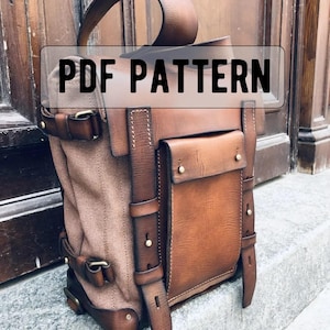 Könnte beinhalten: Ein brauner und beigefarbener Rucksack mit Lederakzenten und dem Text "PDF PATTERN". Die Tasche verfügt über mehrere Taschen, Riemen und Schnallen. Das Design kombiniert Canvas- und Ledermaterialien für eine robuste Ästhetik.
