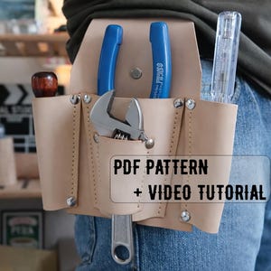 以下が含まれることがあります： 青いハンドル付きのペンチ、レンチ、ドライバーなど、さまざまなツールを備えたタン革のツールベルト。 ベルトは人の腰に装着されています。 画像のテキストは「PDFパターン+ビデオチュートリアル」と表示されています。