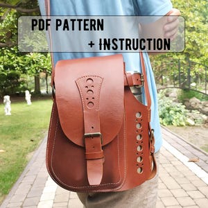 以下が含まれることがあります： フラップとバックル留めの茶色の革製ショルダーバッグ。 バッグには装飾的な切り抜きとステッチが施されています。 テキスト「PDF PATTERN + INSTRUCTION」が画像の上部に表示されています。