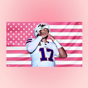 Könnte beinhalten: Ein rechteckiges Wandbanner mit einem Footballspieler in einem weißen Trikot mit der blauen und roten Nummer 17, vor einem rosa-weißen amerikanischen Flaggendesign mit Sternen und Streifen, inklusive vier Metallösen.
