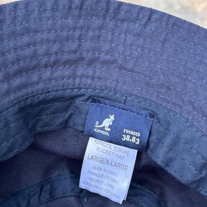 May include: Navy blue Kangol Stripe bucket hat, size large/X-large. The hat features a stitched design and a tag with the Kangol logo and text. Made in China.