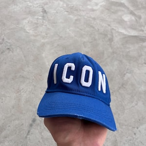May include: A blue baseball cap with the word "ICON" embroidered in white. The cap has a curved brim and a distressed edge. The hat is made of a durable fabric.