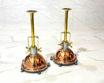 Peut inclure: Une paire de lampes de table dotées d'abat-jours en dôme de cuivre poli, de bases en métal argenté avec des rebords circulaires et de tiges verticales en laiton. Chaque lampe comprend un mécanisme de poignée en laiton fixé par deux écrous.
