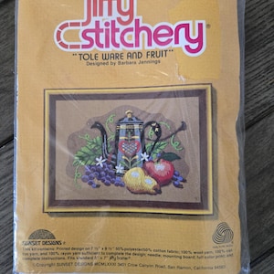 Könnte beinhalten: Ein Jiffy Stitchery-Kit mit dem Titel "Tole Ware and Fruit", entworfen von Barbara Jennings. Das Kit enthält ein gedrucktes Design einer Teekanne, Früchten und Blumen. Es enthält Wolle und passt in einen 12,7 cm x 17,8 cm Rahmen.