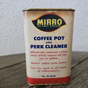 May include: Vintage Mirro Coffee Pot and Perk Cleaner tin. The rectangular tin has a beige background with red and blue text. The top of the tin has a gold rim. The text on the tin reads "MIRRO THE FINEST ALUMINUM" and "COFFEE POT AND PERK CLEANER".