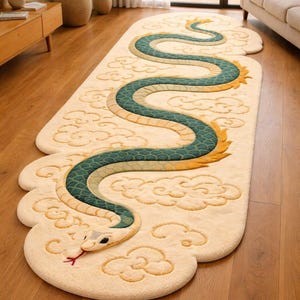 Könnte beinhalten: Ein cremefarbener Teppich mit Schlangenmuster. Die Schlange ist türkis, grün und goldfarben, mit roter Zunge. Der Teppich hat eine wolkenartige Form mit gestickten Wolkendetails. Der Teppich liegt auf einem Parkettboden.