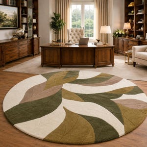 May include: A large circular area rug featuring a repeating pattern of stylised leaves in shades of olive green, sage green, beige, and cream. The rug has a textured, tufted pile surface with defined leaf outlines and a soft, plush appearance.