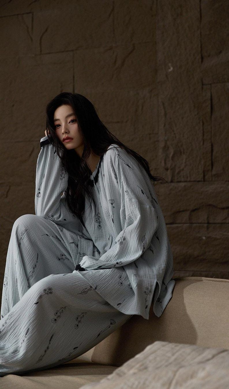 May include: Light blue pajama set with a floral pattern. The long-sleeved top and matching pants are made of a soft, textured fabric. The pajamas are designed for comfort and relaxation.