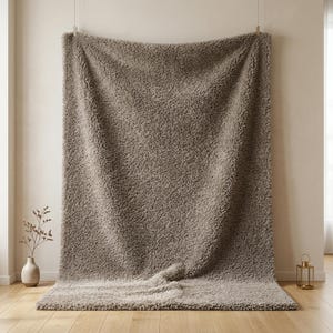 May include: A large, rectangular, taupe-colored faux fur throw blanket with a thick, shaggy, and textured pile. The blanket is suspended from the top edge, draping downward to cover the floor surface with soft, voluminous folds and ripples.