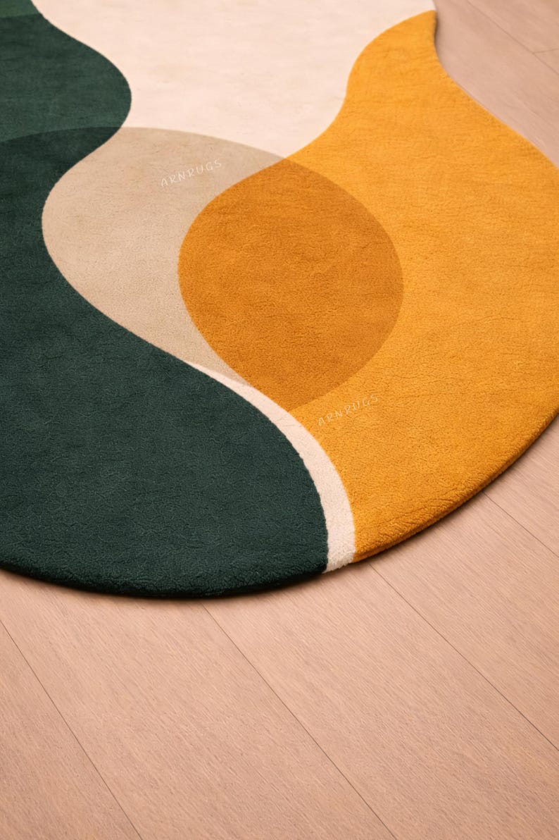 May include: A round rug with an abstract design. The rug features a dark green, tan, and mustard yellow color palette. The design includes curved shapes and a white border. The rug is on a wooden floor.