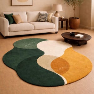May include: A modern, abstract area rug with a unique, flowing design. The rug features a combination of colors, including deep green, beige, white, and golden yellow. The text "ARNRUGS" is visible on the rug. The rug is placed on a wooden floor.
