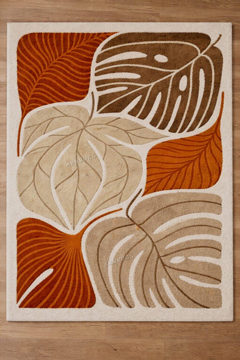 May include: A rectangular rug featuring a cream backdrop and a design of oversized, stylised leaves in brown, tan, and orange hues. The leaves display intricate vein patterns, and the overall aesthetic evokes mid-century modern art.