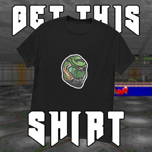 May include: Black t-shirt with a green and tan helmet graphic. White block letters above and below read "GET THIS SHIRT". The background is a pixelated video game scene.