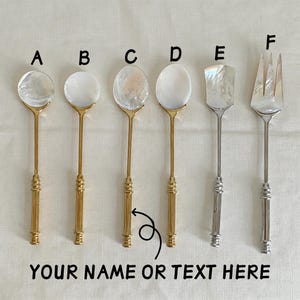 May include: A selection of serving utensils featuring mother-of-pearl heads and decorative handles. The set includes spoons, a spatula, and a fork. The text "YOUR NAME OR TEXT HERE" is at the bottom of the image.
