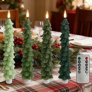 Puede incluir: Cuatro velas LED verdes con forma de árbol de Navidad con mando a distancia. Las velas varían en tonos de verde, cada una con una base blanca y una llama LED parpadeante. El mando a distancia tiene varios botones.