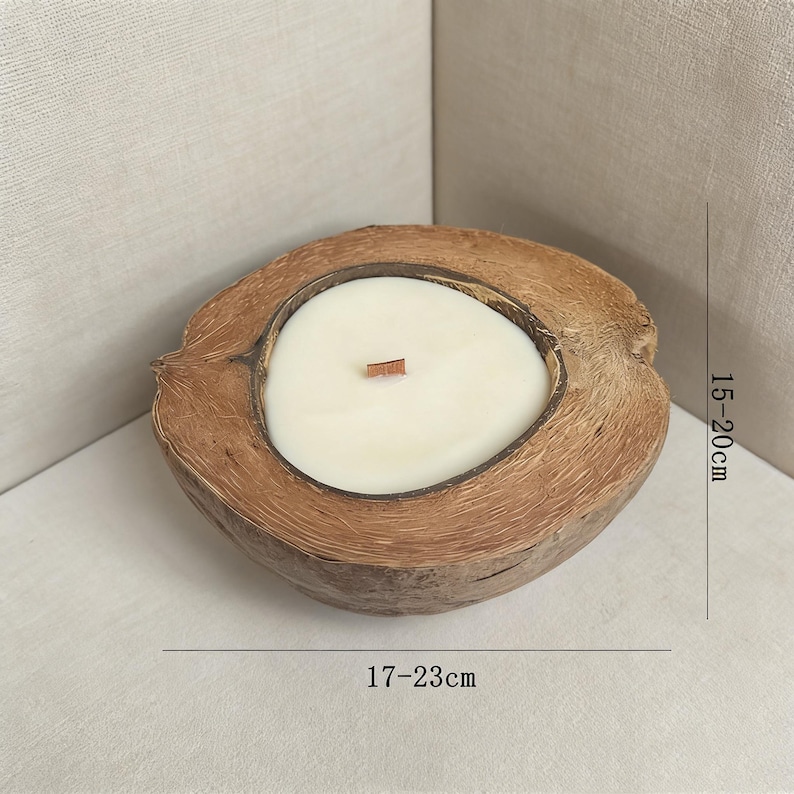 May include: A coconut shell candle with a white wax interior and a wooden wick. The candle is nestled in a natural coconut shell, measuring approximately 17-23 cm in length and 15-20 cm in height. The candle is a natural home decor item.