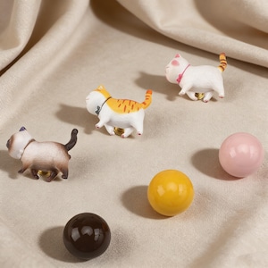 Peut inclure: Ensemble de boutons de meubles décoratifs en forme de chats et sphériques. Les boutons en forme de chat sont blancs, orange et marron avec des détails noirs et dorés. Les boutons sphériques sont marron, jaunes et roses. Idéal pour les meubles.