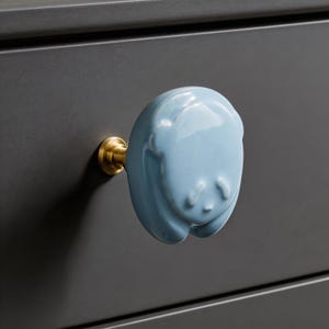 Puede incluir: Una taza de cerámica blanca con un asa negra y el texto "But First, Coffee" en negro y negrita. La taza está sobre una superficie de madera. La taza mide aproximadamente 10 cm de alto.