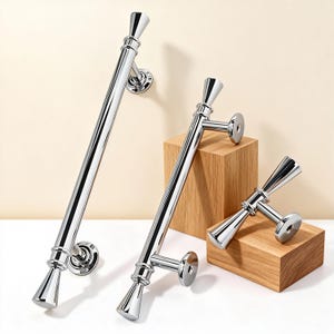 Pode incluir: Puxadores de porta cromados brilhantes em vários tamanhos. Os puxadores têm um design elegante e moderno com uma forma cónica em cada extremidade e uma base circular. São exibidos em blocos de madeira.