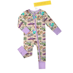 May include: A beige baby sleeper with a colorful pattern of cartoon cars. The sleeper has a purple zipper, cuffs, and collar. The tag at the top reads, "For child's safety, garment should fit snugly. This garment is not flame resistant. Loose-fitting garment is more likely to catch fire."