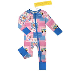 May include: Pink and blue patchwork-style baby sleeper with a full-length zipper. The sleeper features a repeating pattern of cartoon characters, bows, and school buses. The cuffs and neckline are blue, and the text "ick ticky bubble gum!" is visible.