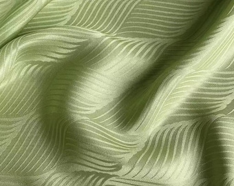 May include: A close-up of a green fabric with a wavy pattern. The fabric is smooth and silky.