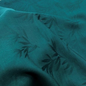 May include: Teal fabric with a subtle embossed leaf pattern. The fabric has a smooth, silky texture.