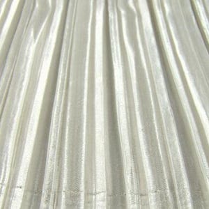 May include: A close-up of a white pleated fabric with a subtle shimmer. The fabric has a smooth, silky texture.