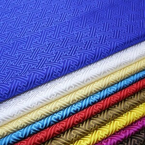May include: A stack of fabric in various colors, including blue, white, gold, turquoise, red, brown, yellow, pink, and purple. The fabric has a geometric pattern and a slightly textured surface.