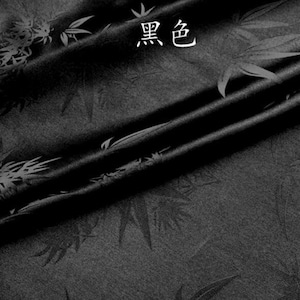 Puede incluir: Tela negra con un sutil patrón en relieve de hojas de bambú. La tela está doblada de manera que se muestra la textura y el brillo del material.